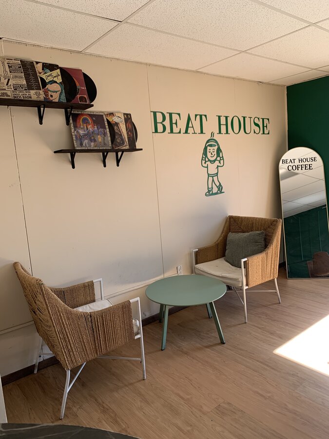 Área de asientos de Beat House, sillas de mimbre y el logo pintado en el piso